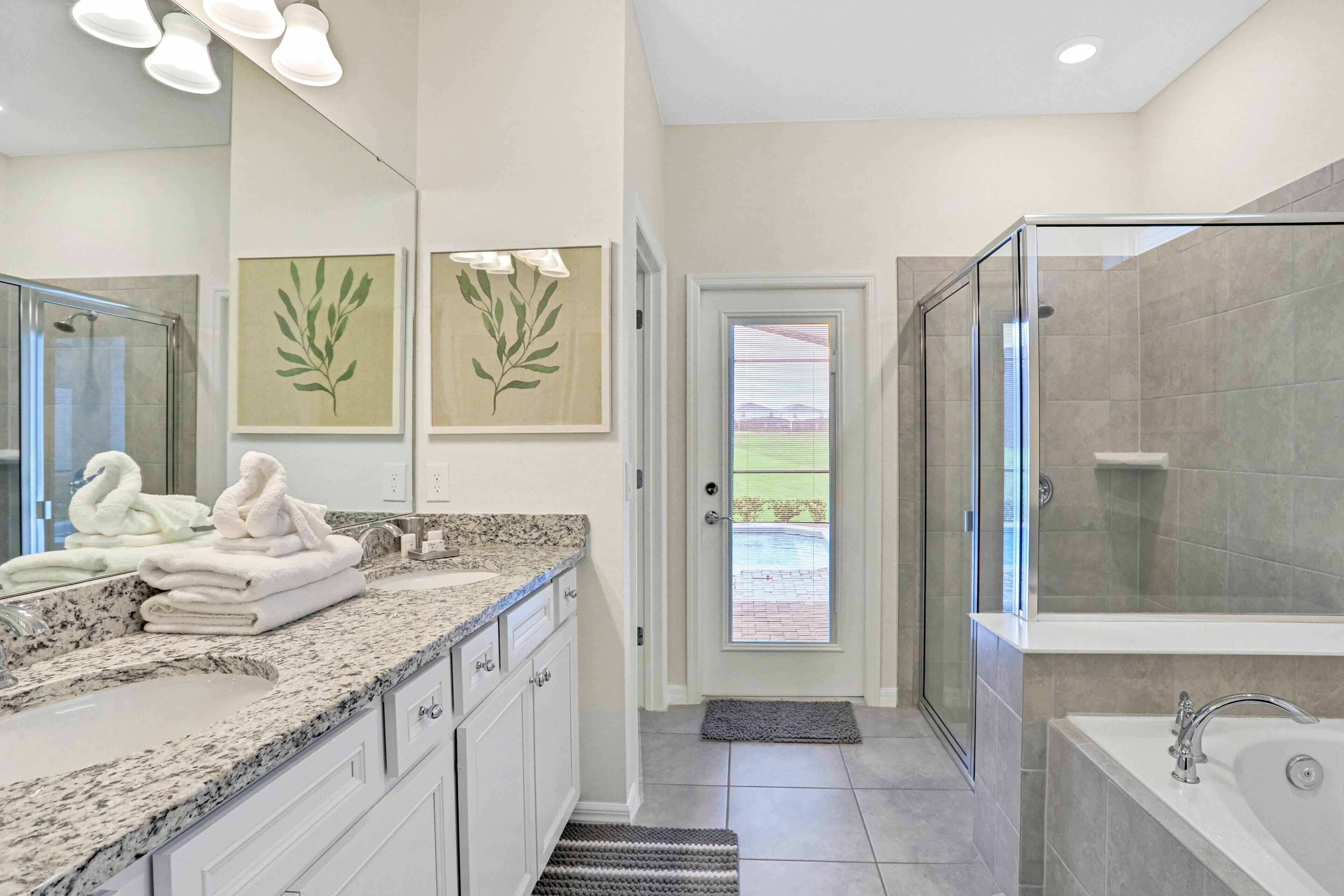 Une salle de bain moderne avec une douche à parois de verre, un grand miroir et un comptoir en granit.