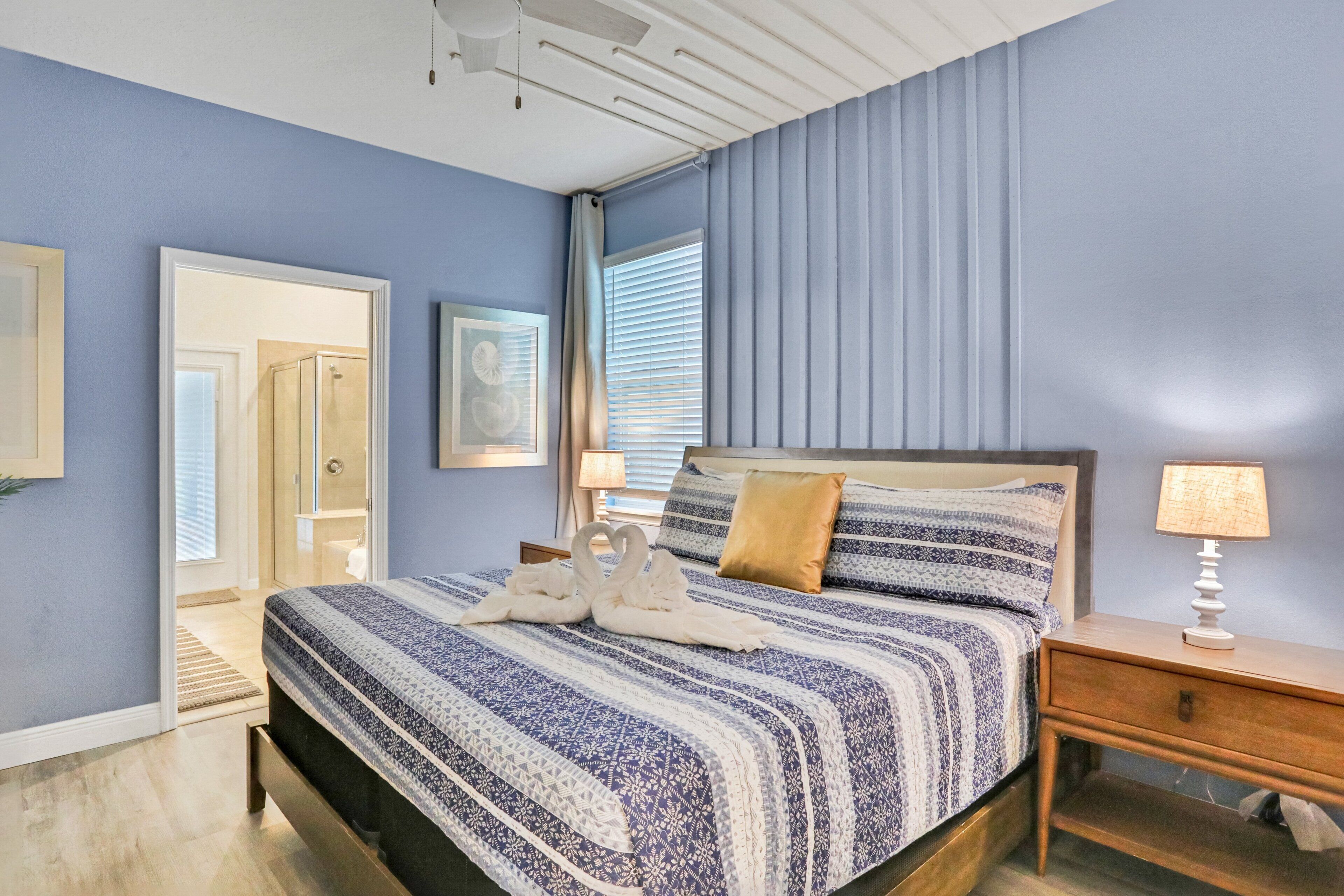 Un dormitorio con cama, mesita de noche y puerta que da a un baño.