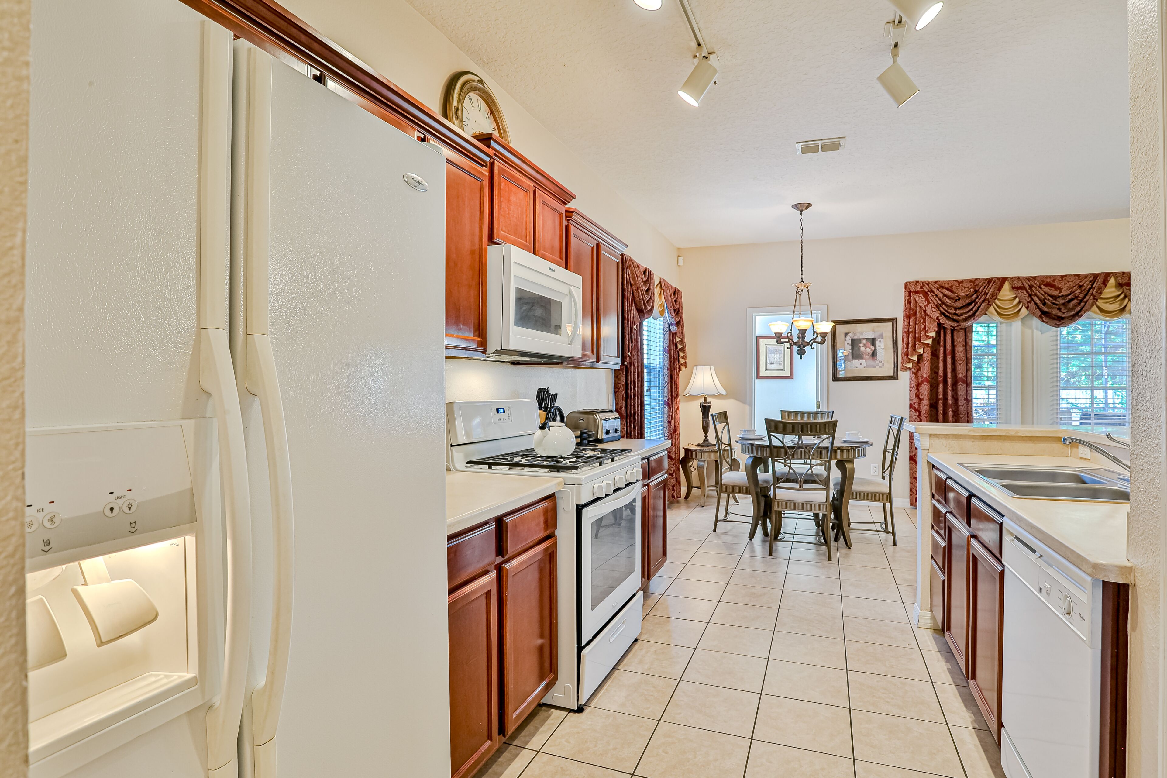 A kitchen with wooden cabinets, a microwave, stove, oven, and a dining table with chairs.