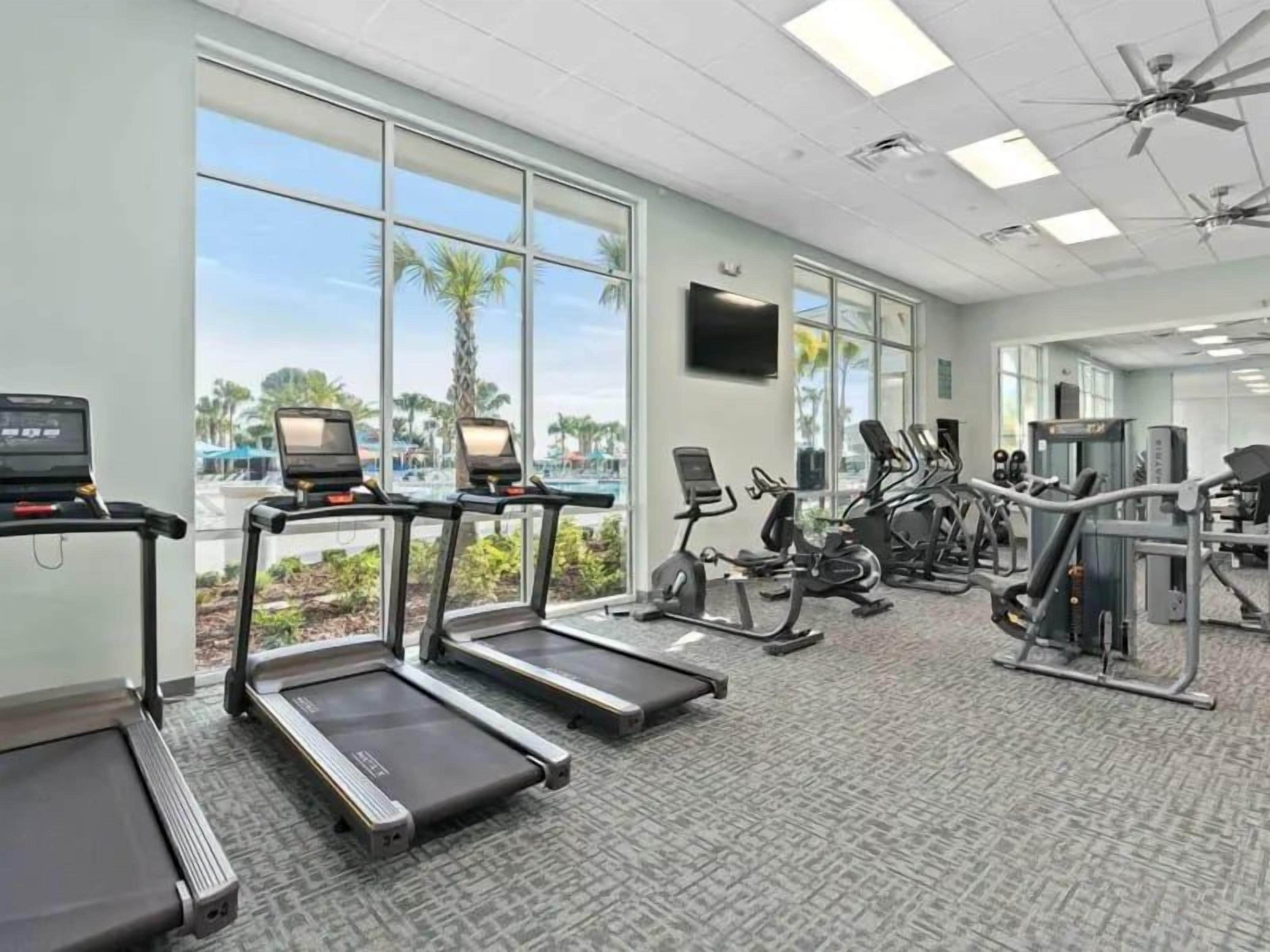 Une salle de sport équipée de tapis de course, de vélos d’appartement et d’appareils de musculation.
