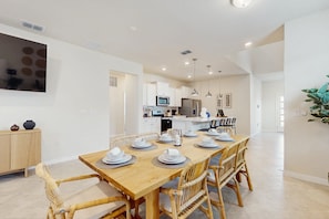 A modern kitchen with white cabinets, a dining table set with plates, and a large window. - Amazing Home With Outdoor Patio, Wifi, & Close to Local Attractions Near Orlando (Clermont)