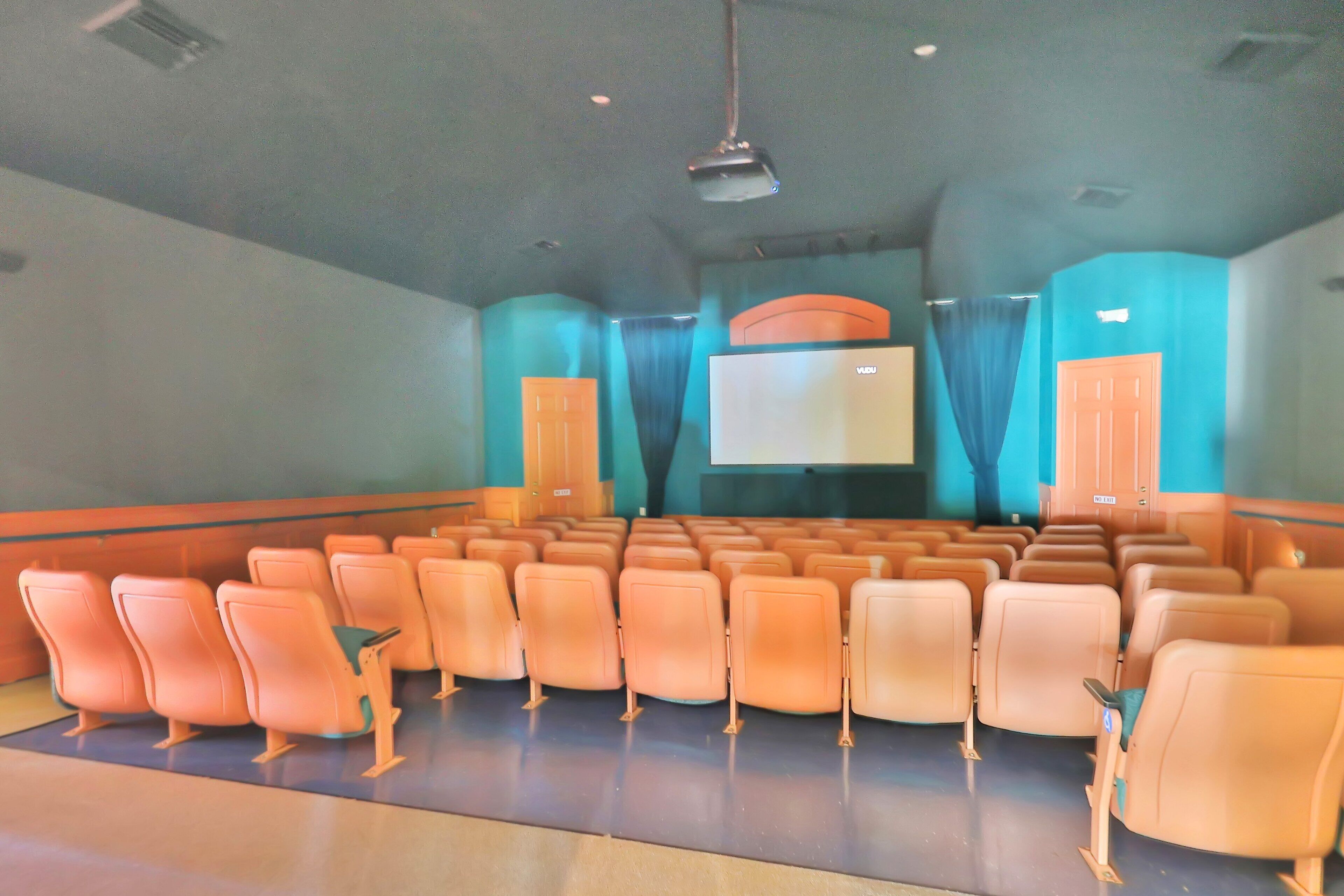 Une salle de cinéma avec des rangées de sièges, un grand écran et des rideaux.