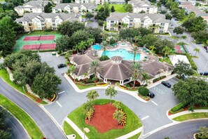 A residential area with a swimming pool, tennis courts, and a parking lot. - Spacious Condo With Shared Pool, Tennis Court, Game Room, & More (Kissimmee)