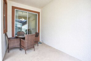 A balcony with wicker furniture, a sliding glass door, and a view of the interior. - Modern Luxury Townhome With hot tub & Private Pool - Near Theme Parks (Davenport)