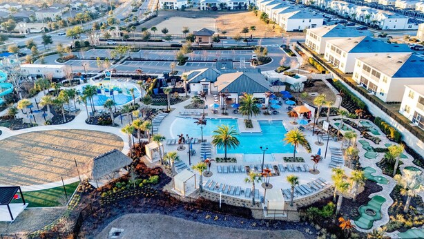 An aerial view of a resort with a central swimming pool, lounge areas, and a parking lot. - Modern Luxury Townhome With hot tub & Private Pool - Near Theme Parks (Davenport)