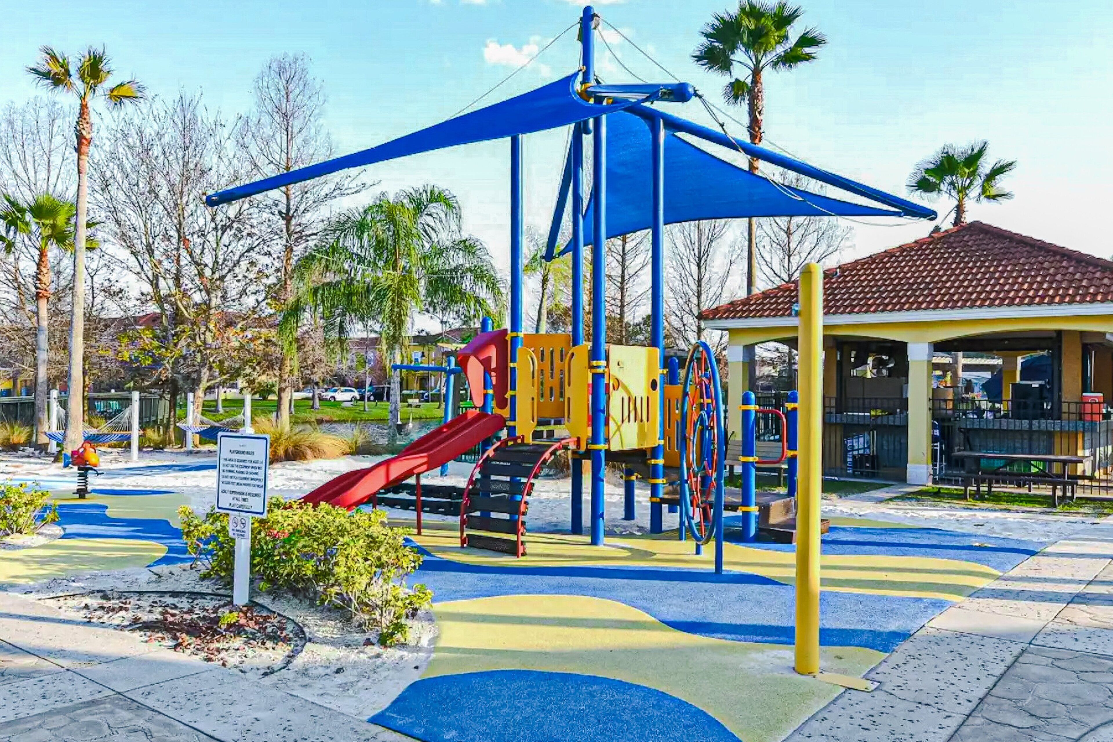 Un parque infantil con tobogán, estructuras para escalar y una zona de estar techada.
