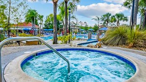 A hot tub surrounded by palm trees and a pool area. - Beautiful & Spacious Resort Home in the Heart of Central FL (Kissimmee)
