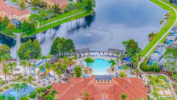 An aerial view of a resort with a central pool, surrounding pathways, and a water body. - Beautiful & Spacious Resort Home in the Heart of Central FL (Kissimmee)
