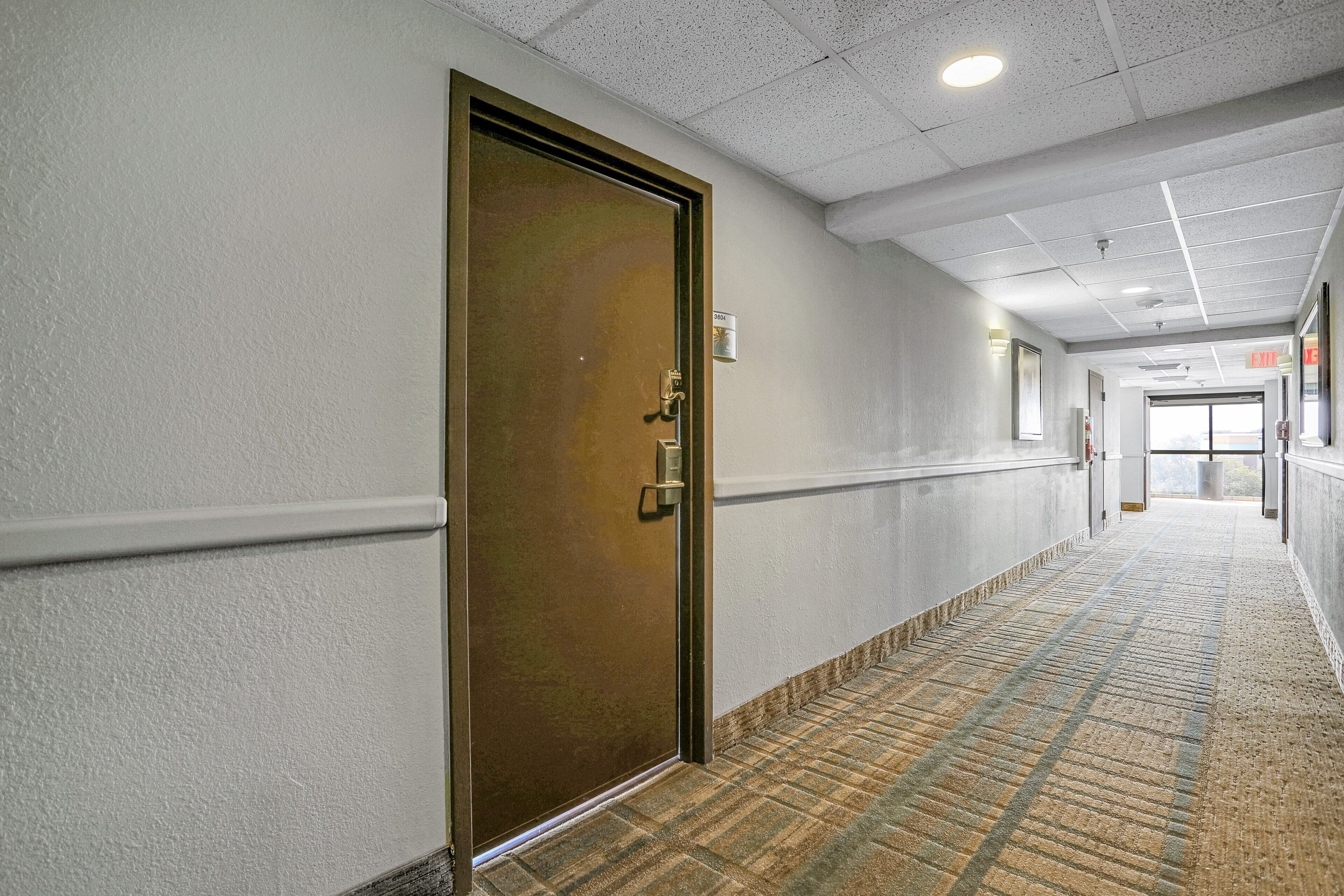 A hallway with a patterned carpet, a door with a brass handle, and a sign indicating room number 403.