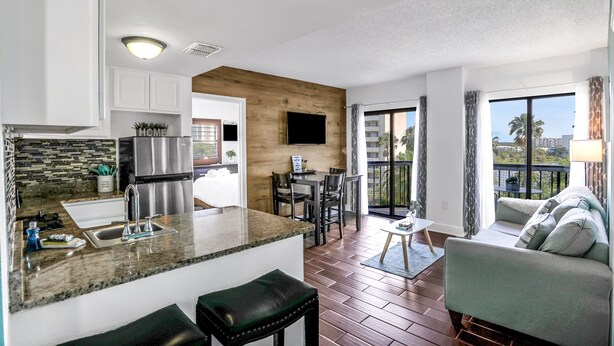 A modern kitchen with a granite countertop, stainless steel appliances, and a dining area with a table and chairs.