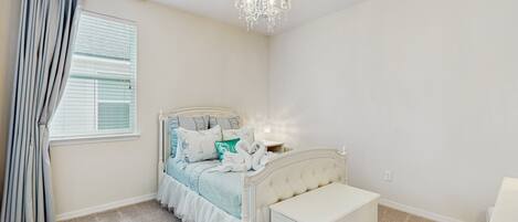 A bedroom with a bed, bedside table, and a chandelier.