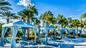 A poolside area with blue canopies and lounge chairs. - Solara Joy Disney-themed Retreat in Kissimmee With Stellar Resort Amenities (Kissimmee)