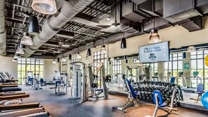 A gym with various exercise equipment, including treadmills, dumbbells, and weight machines. - Solara Joy Disney-themed Retreat in Kissimmee With Stellar Resort Amenities (Kissimmee)