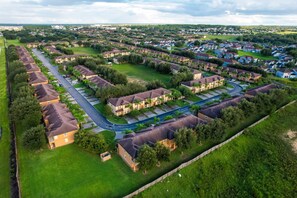 A residential area with multiple houses, green lawns, and a road. - Townhouse Near Theme Parks & Shopping With Pool Access (Davenport)