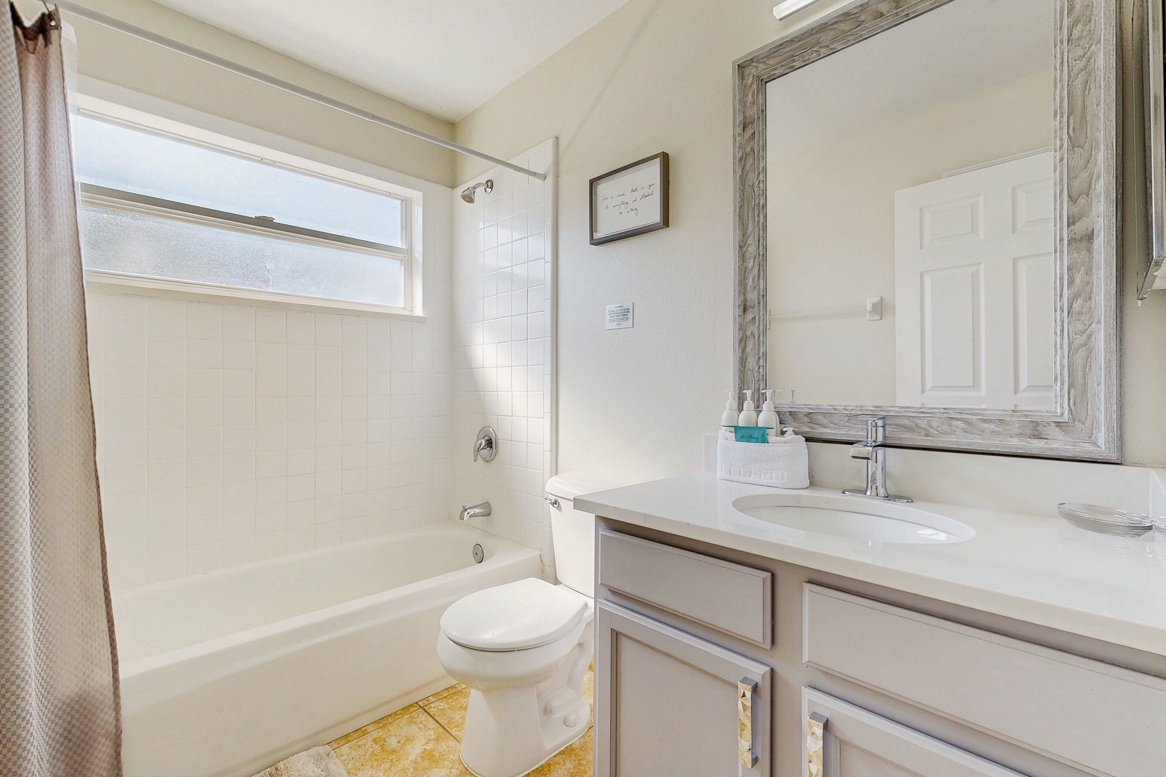 A bathroom with a bathtub, toilet, sink, and a large mirror.