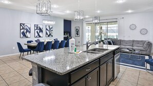 A modern kitchen with granite countertops, a central island, and pendant lighting. - Gorgeous Home With Private Pool With Spa, Pool Table & gas Grill (Kissimmee)