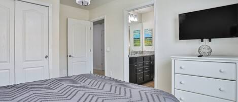 A bedroom with a bed, a dresser, a television, and a chandelier.