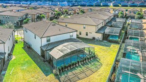 A residential area with houses, a covered swimming pool, and a clear sky. - Gorgeous Home With Private Pool With Spa, Pool Table & gas Grill (Kissimmee)