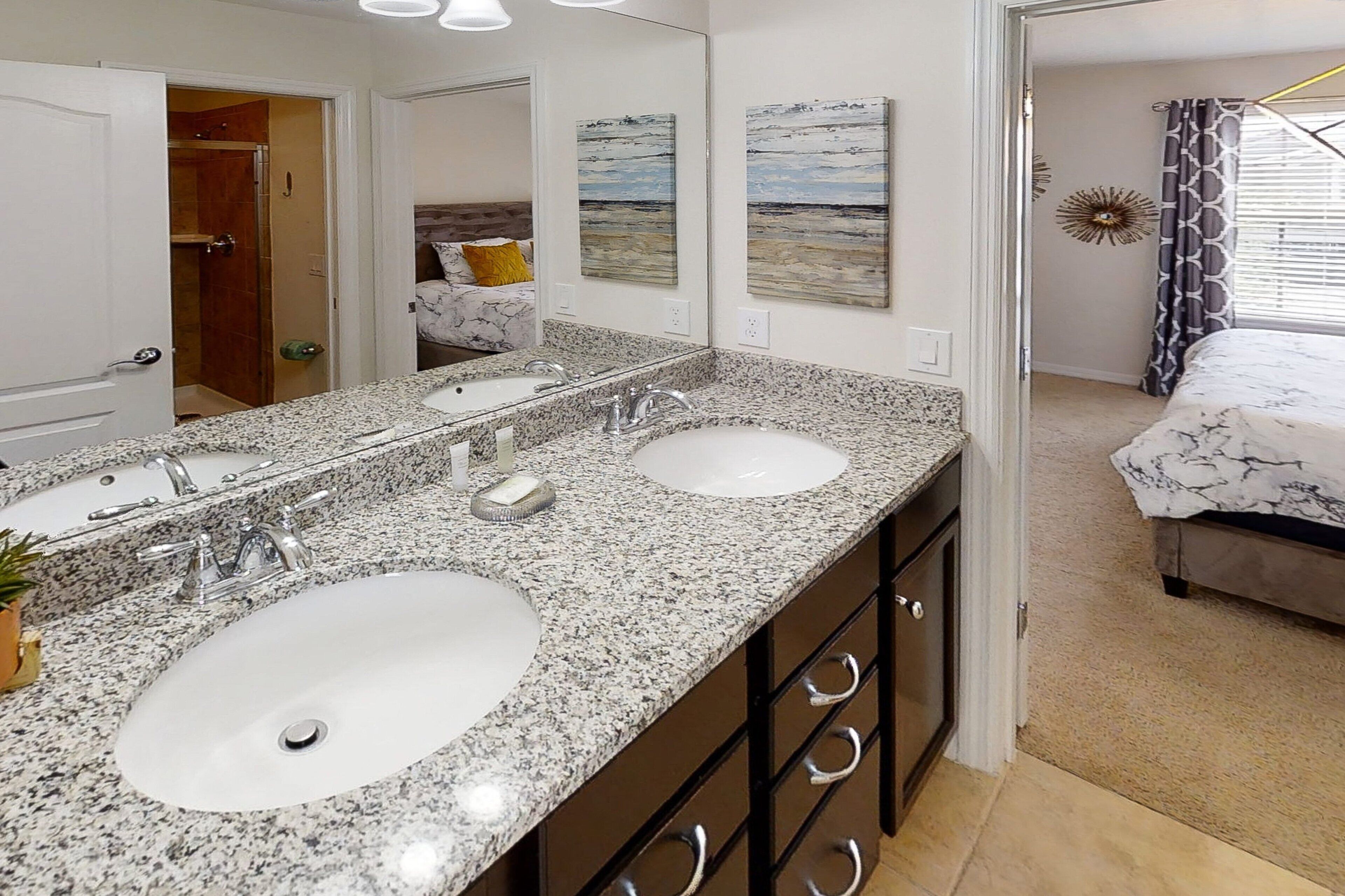A bathroom with two sinks, a large mirror, and a walk-in shower.