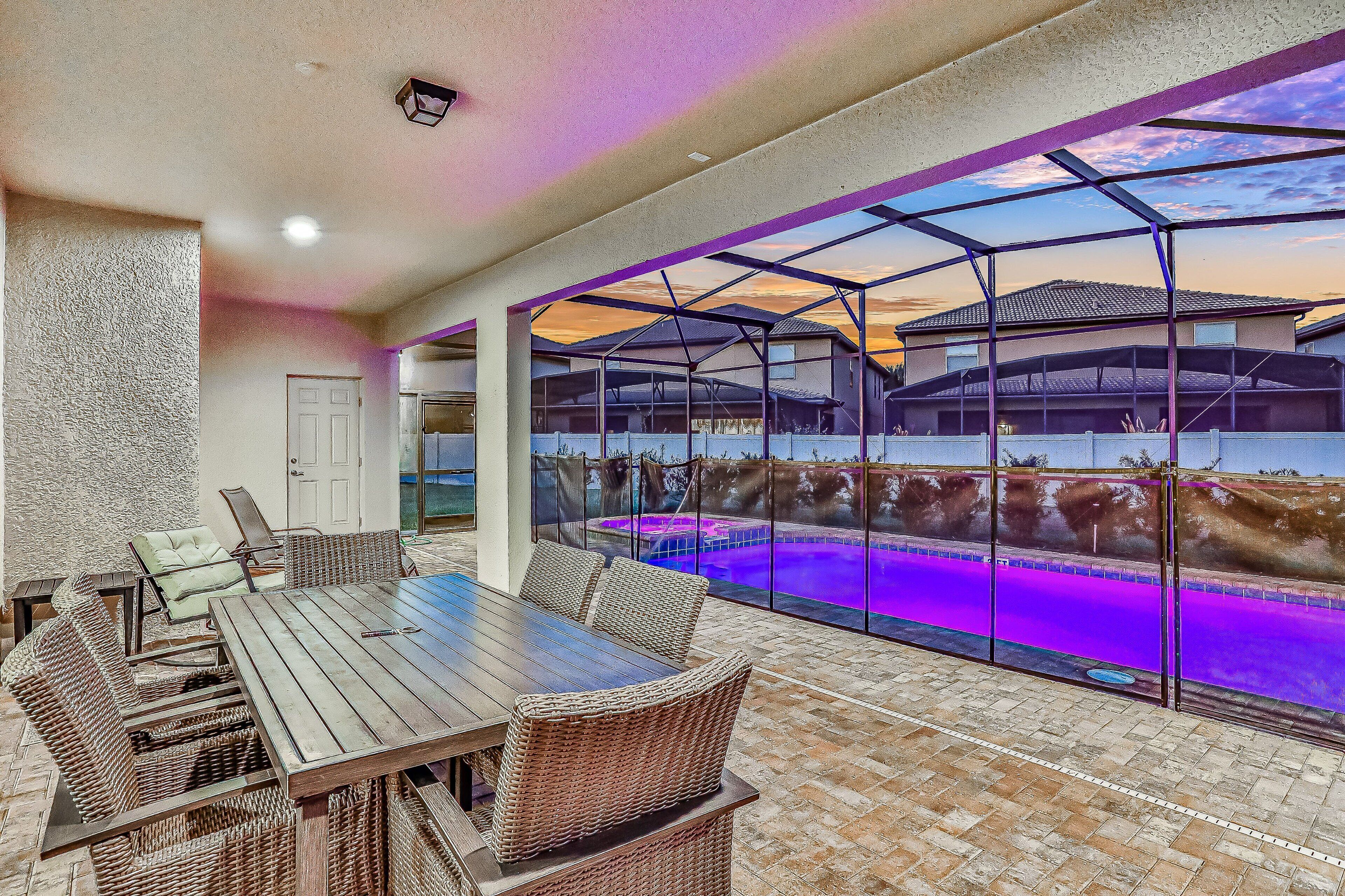An outdoor patio with a pool, covered seating, and a view of a house.