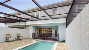 A modern outdoor pool area with a covered patio, two lounge chairs, and a table. - Beautiful Home With Private Pool and Space for the Whole Family (Davenport)