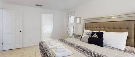 A bedroom with a bed, a ceiling fan, a nightstand, and a door.