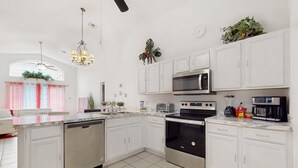 Una cocina moderna con armarios blancos, electrodomésticos de acero inoxidable, lavavajillas y horno empotrado.