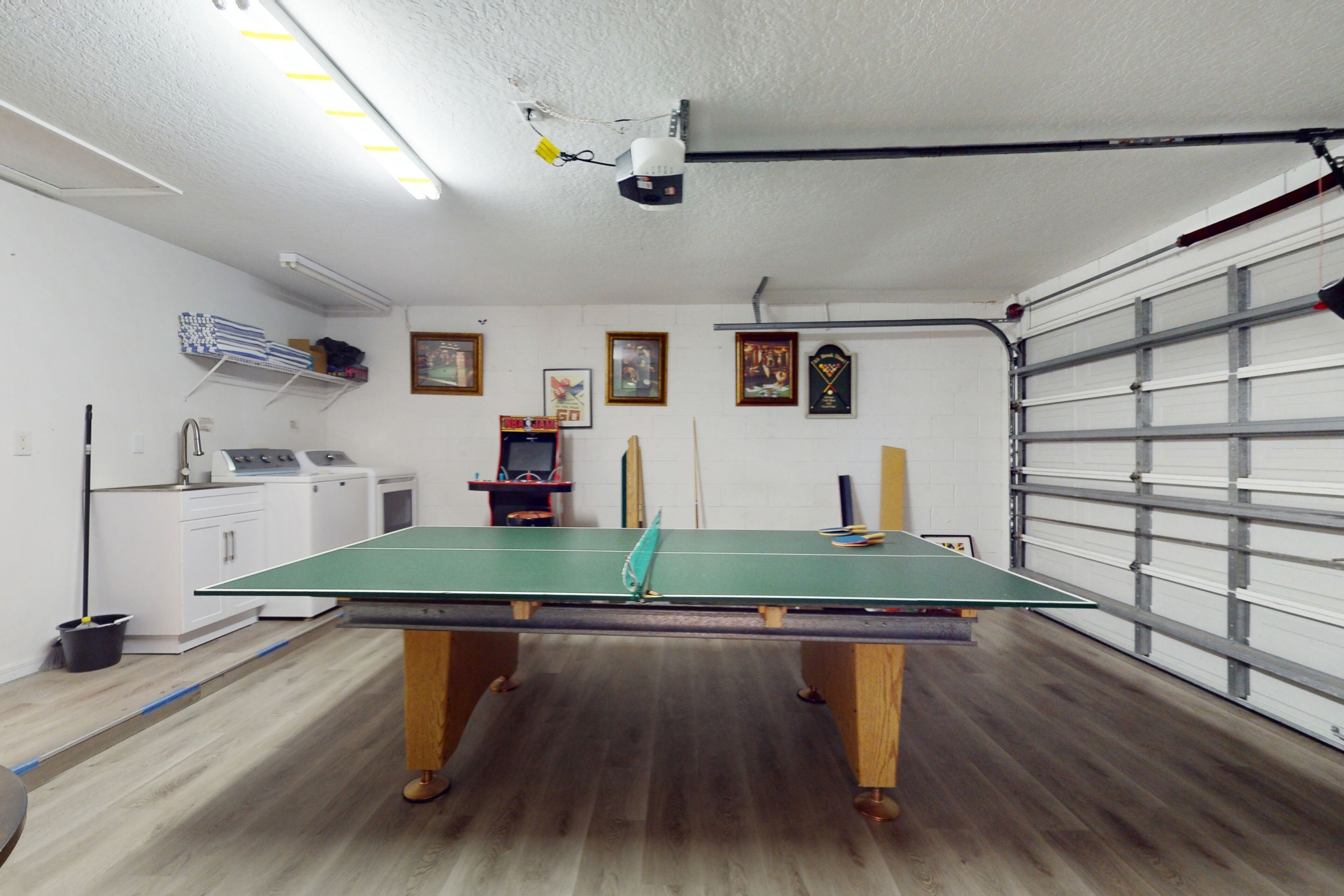 Une pièce avec une table de ping-pong, un lave-linge et une porte de garage.