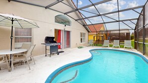 Una piscina interior con techo de vidrio, una parrilla y sillones de descanso.