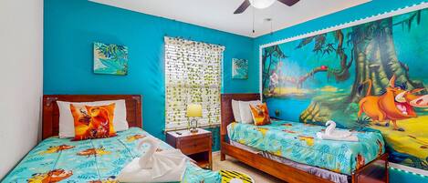 A bedroom with two beds, a ceiling fan, a window with blinds, and a mural on the wall.