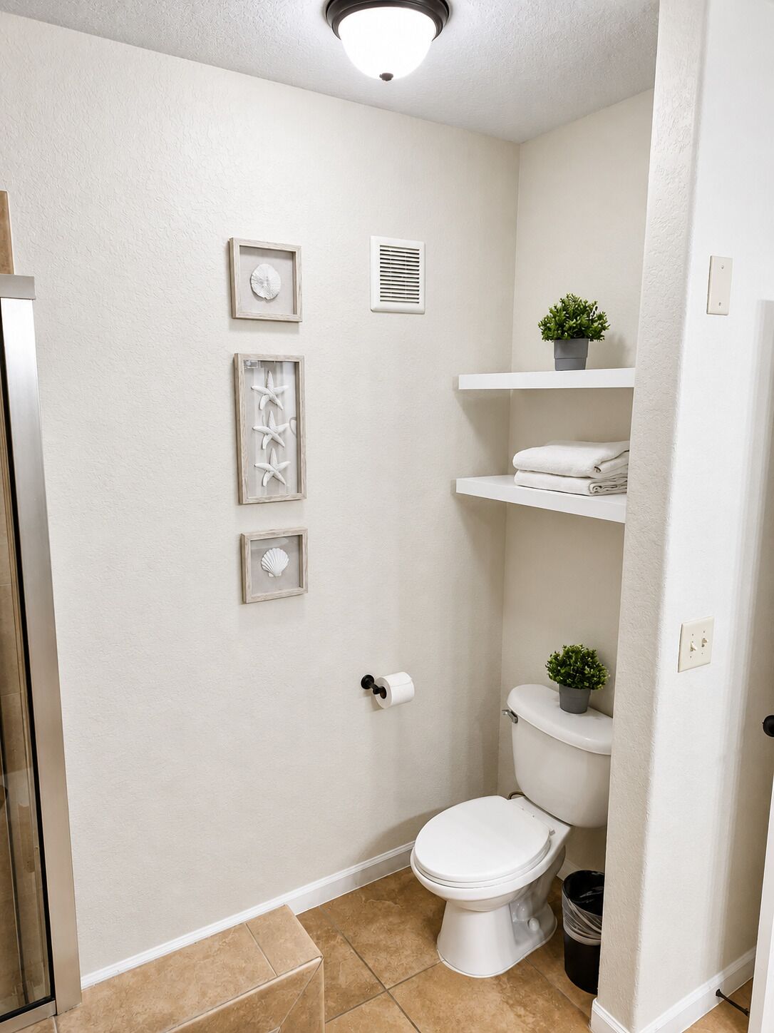 Ein Badezimmer mit Toilette, Waschbecken, Dusche und einem Ablagefach mit Handtüchern.