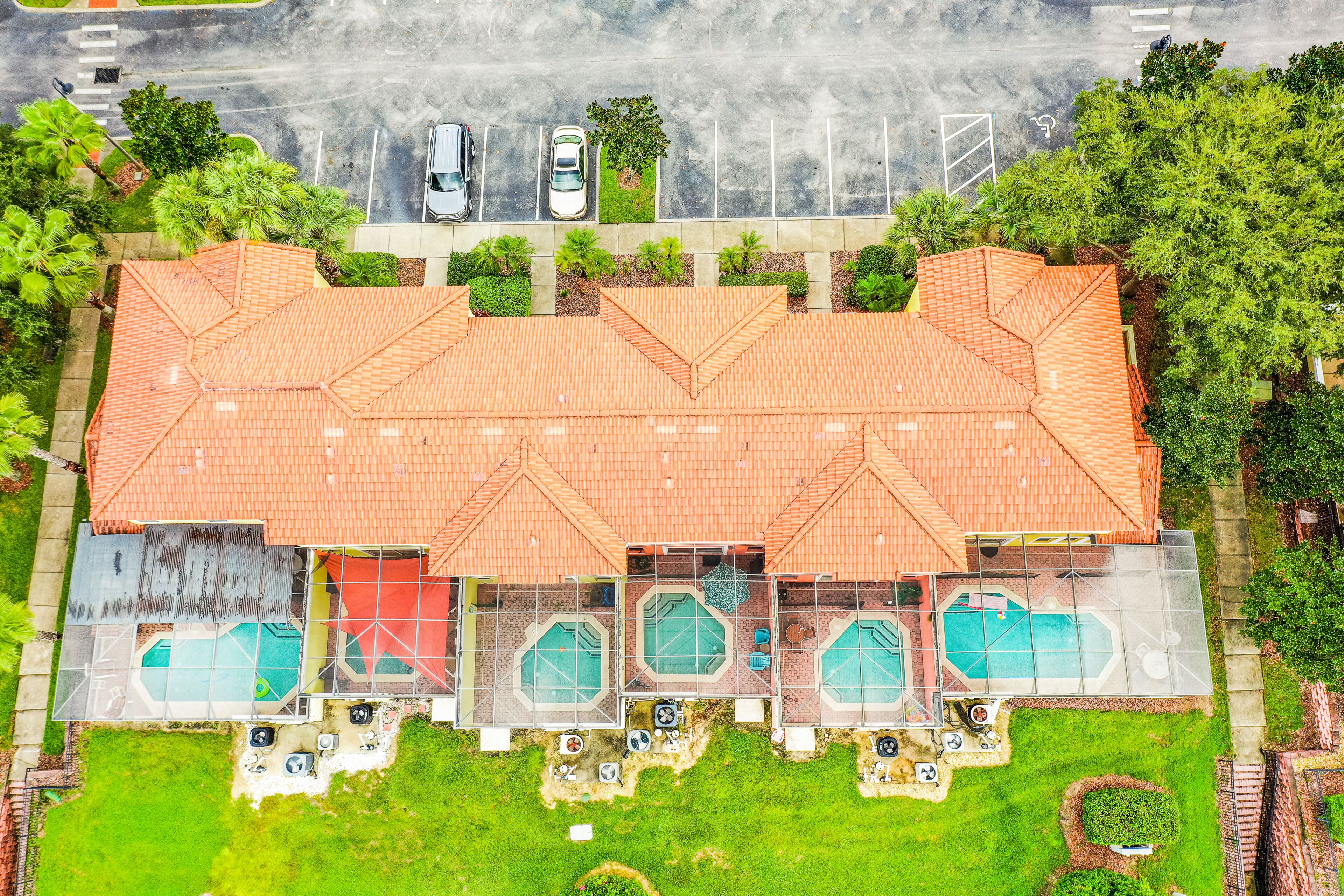 Vue aérienne d’un hôtel doté d’un grand toit, de plusieurs piscines et d’un parking.