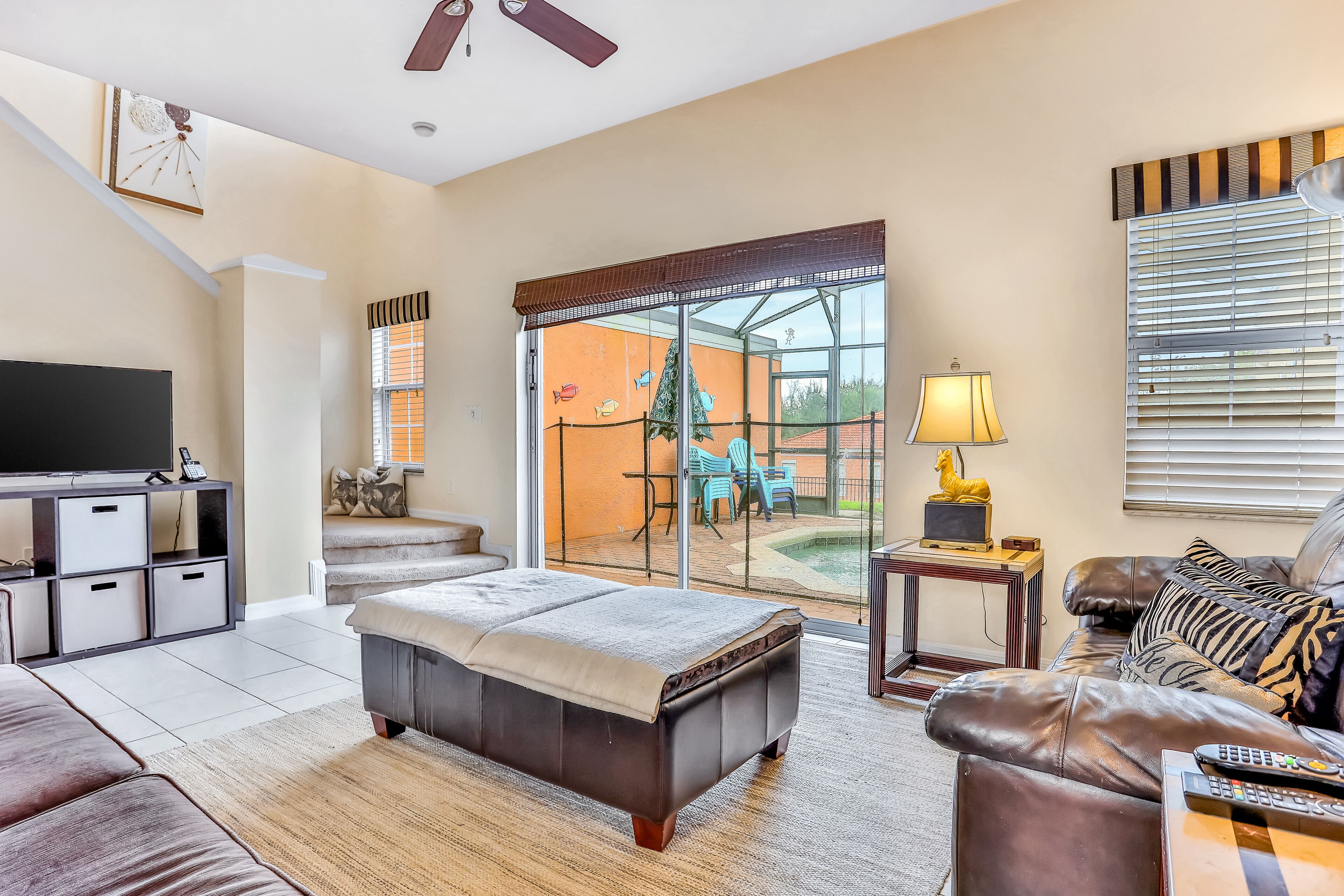 A spacious living room with a large flat-screen TV, a sofa, a coffee table, and a dining area with outdoor seating.