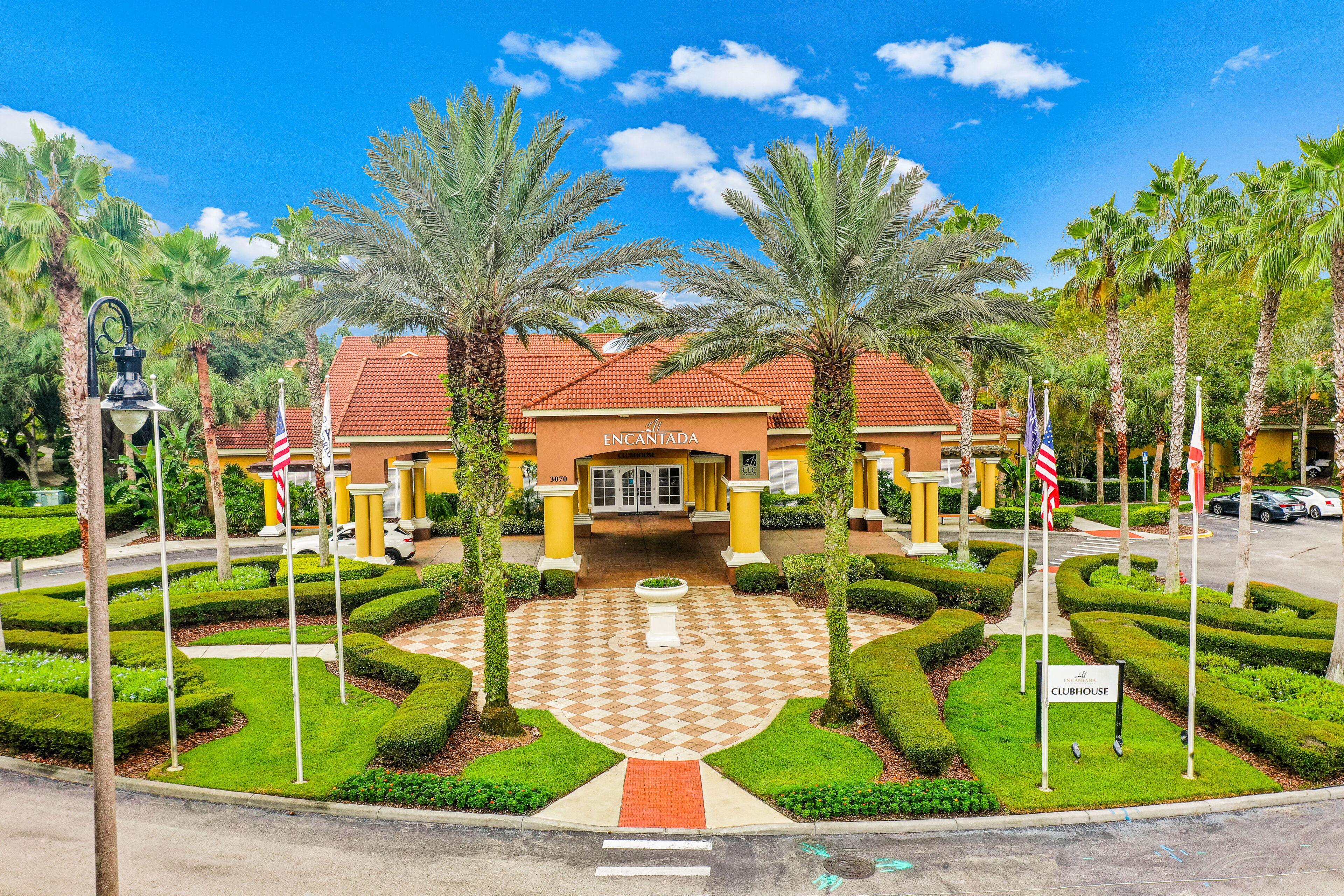 A hotel with a central courtyard, palm trees, and a red-tiled roof.