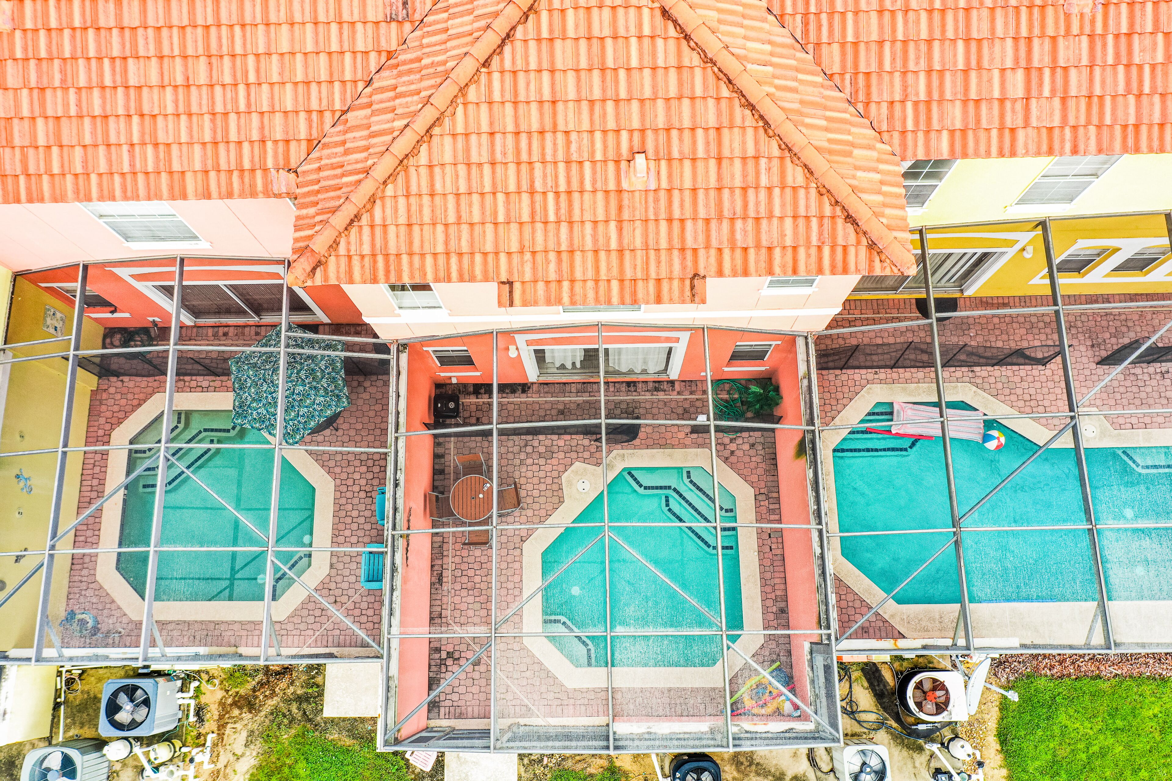 A multi-story building with a tiled roof, multiple swimming pools, and outdoor seating areas.