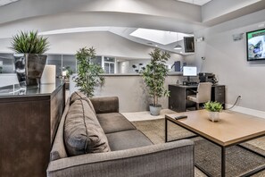 A modern office space with a sofa, a small table, and potted plants. - Two-story, Dog-friendly gem Near Theme Parks With Pool, Central AC & On-site gym (Kissimmee)