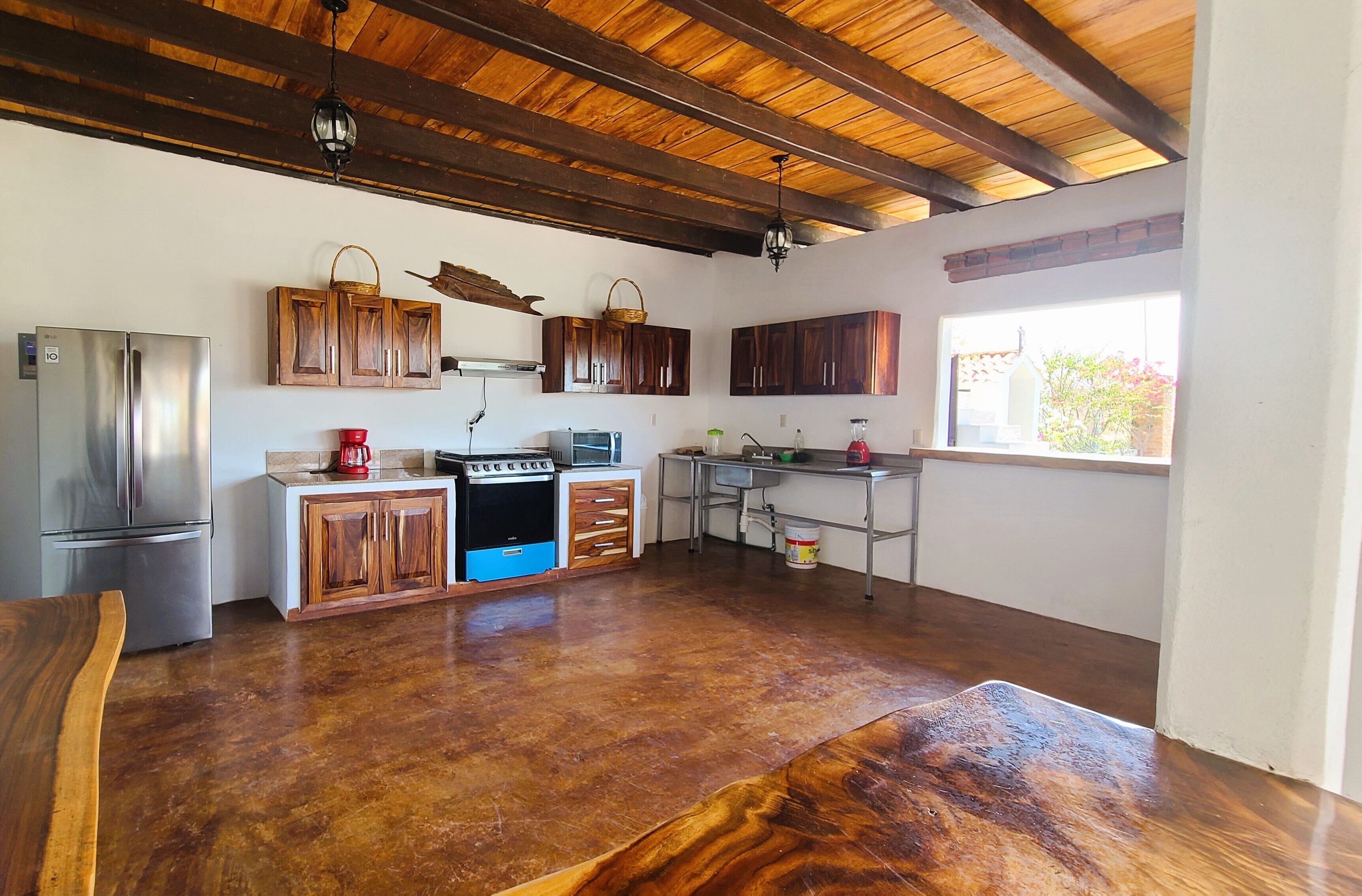 Una cucina con mobili in legno, un frigorifero in acciaio inossidabile, un fornello e una finestra che offre luce naturale.