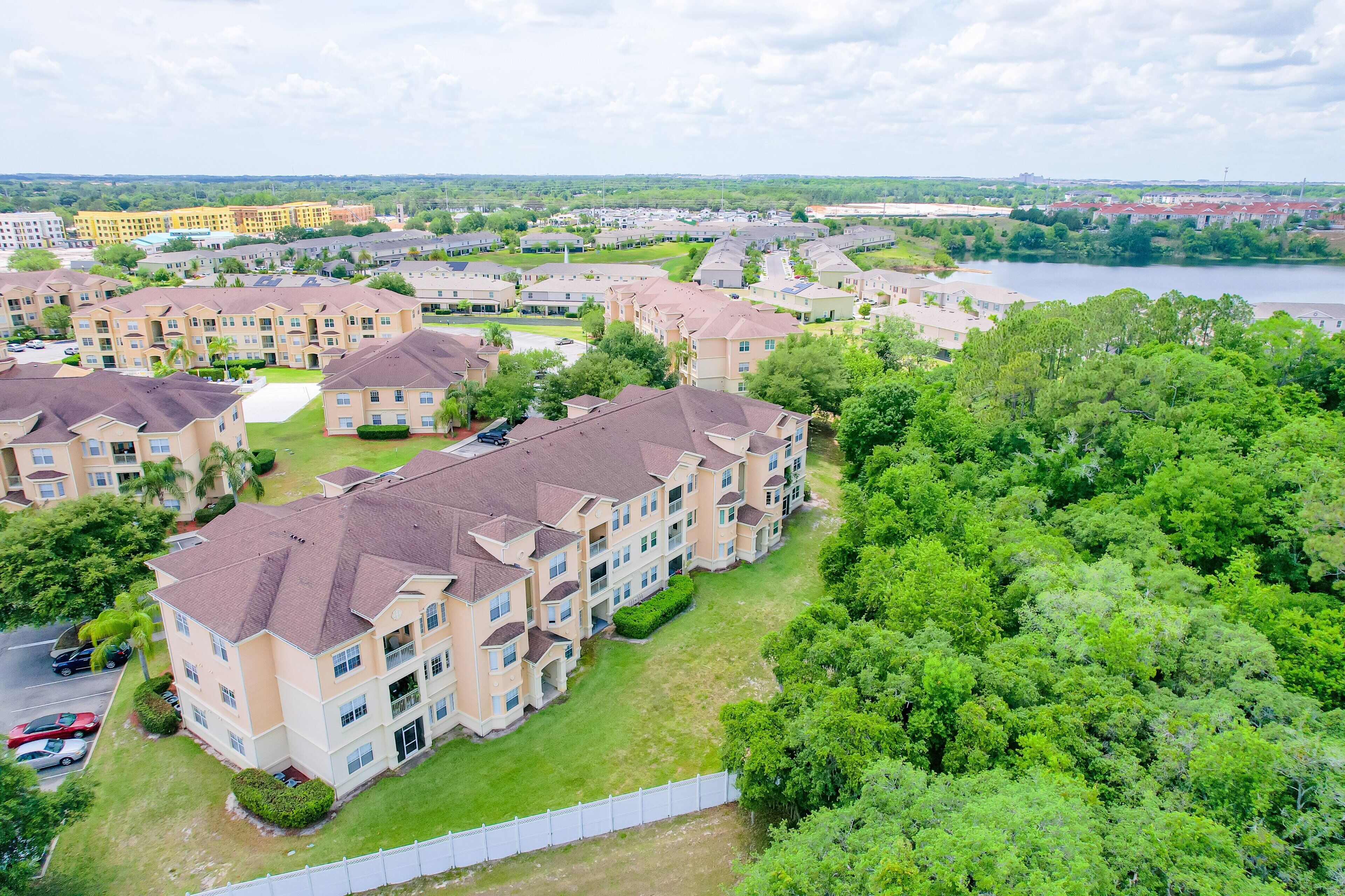 Un complejo residencial con varios edificios de apartamentos, césped verde y un río al fondo.