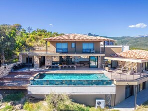 Ein zweistöckiges Haus mit Pool, Außenbereich und Blick auf die Berge.