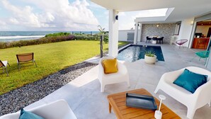 Ein moderner Außenbereich mit Pool, Sitzgelegenheiten und Meerblick.