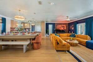 A spacious living area with a pool table, a sofa, and a neon sign.