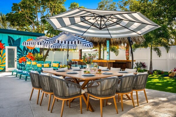 An outdoor dining area with a large umbrella, wicker chairs, and a table set for four.