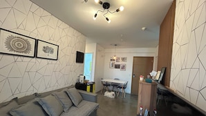 Een moderne woonkamer met een bank, eettafel en een keuken op de achtergrond.
