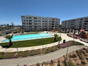 A residential building with a swimming pool, playground, and landscaped garden.