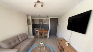 A living room with a sofa, a coffee table with a plant, a TV, and a wooden cabinet. - Your Perfect Getaway in La Serena! (La Serena)