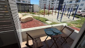 A balcony with a table and chairs, a view of a playground, and apartment buildings in the background. - Your Perfect Getaway in La Serena! (La Serena)