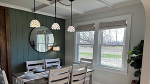 Un espace repas comprenant une table en bois, des chaises, un miroir et des lampes suspendues.