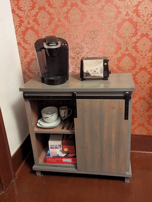 Eine Küchenzeile mit Kaffeemaschine, Toaster und einer Packung Rombus Classic Kaffeekapseln.