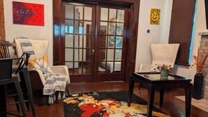 Una sala de estar con un sofá, sillas, una mesa de centro, una alfombra colorida y una puerta de madera.