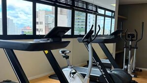 Un gimnasio con cintas de correr, elípticas y una bicicleta estática.